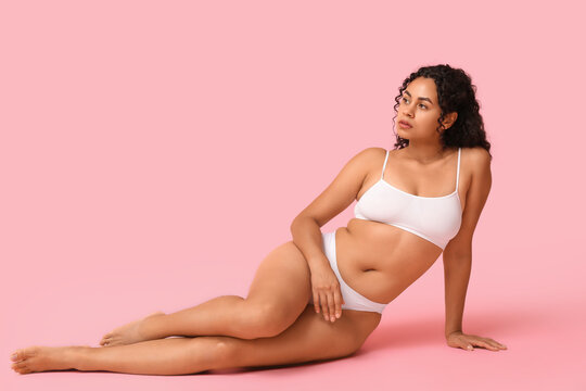 Body positivity and self love, young woman with natural curves in white lingerie posing on pink background for beauty and wellness advertising campaign