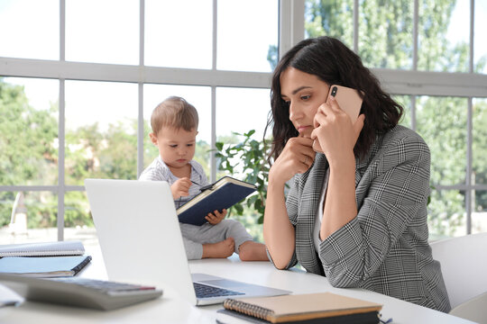 Work-life balance and parenting challenges, mother working from home on laptop while caring for toddler in bright office with window light