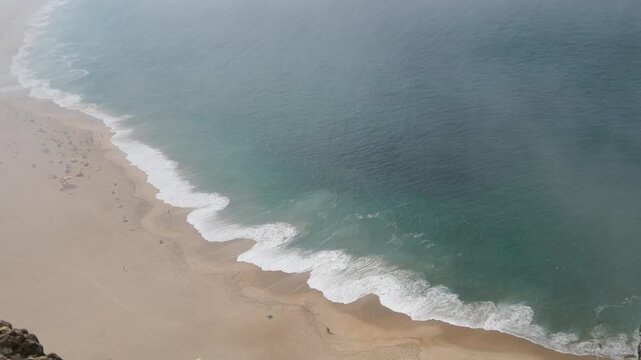 Heavy fog rolling in over Praia do Norte in Nazar&eacute; Portugal with large ocean waves view from high overlook