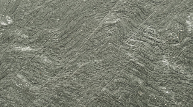 Folded metamorphic rock texture showing foliated wavy mineral grain and scratches