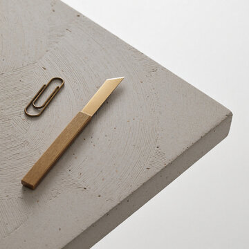 Brass paper knife on microcement desk surface