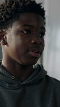 Vertical video: Gesturing teen student answering off-camera prompt in classroom, hoodie, whiteboard