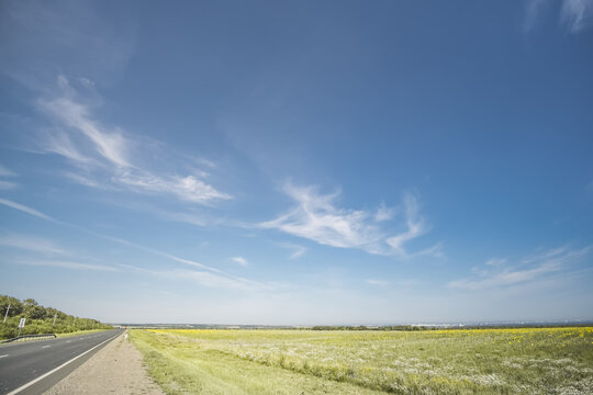 Summer cloudy sky over the Kazakh steppe and fields; white clouds against a blue sky in sunlight; fine weather in June; background landscape