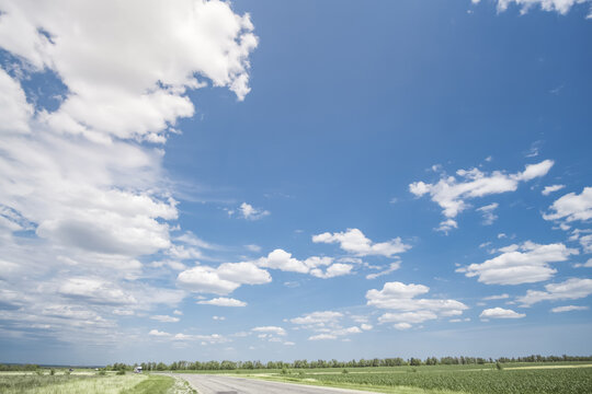 Summer cloudy sky over the Kazakh steppe and fields; white clouds against a blue sky in sunlight; fine weather in June; background landscape