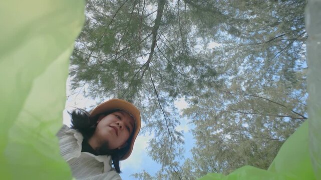 The view from the trash heap. POV: A women picks up trash against a blue sky with clouds. Wide angle shot. Fisheye. People taking care of nature. Ecology in danger. Stop the overproduction.