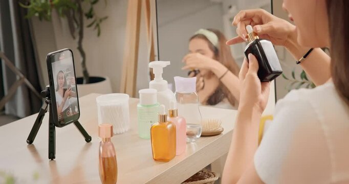 Asian woman beauty influencer, content creator filming skincare product review on smartphone at home. Gen Z lifestyle social media trends. digital marketing, promotions, cosmetic branding vlogs.