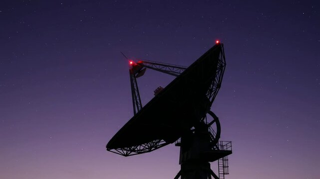 Satellite dish antenna silhouette at night against starry purple twilight sky, radar communications receiver for science technology broadcast