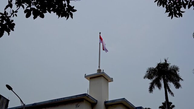 Indonesian flag waving on top of the historic Hotel Yamato building in Surabaya during national independence commemoration under cloudy sky