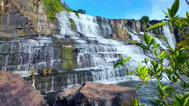 Slow-motion footage of Pongour Waterfall in Lam Dong Province, Vietnam, showcasing magnificent multi-tiered cascades flowing over ancient rock formations in the morning.