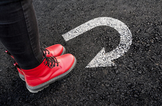 Business Pivot and Rethinking Strategy: A Woman in Red Boots Standing at a Strategic U-Turn Junction.