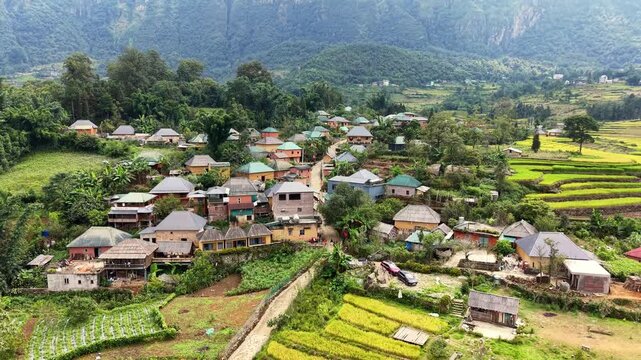 Aerial pullback revealing a Ha Nhi village with yellow earthen walls and brown rooftops in Y Ty, Vietnam