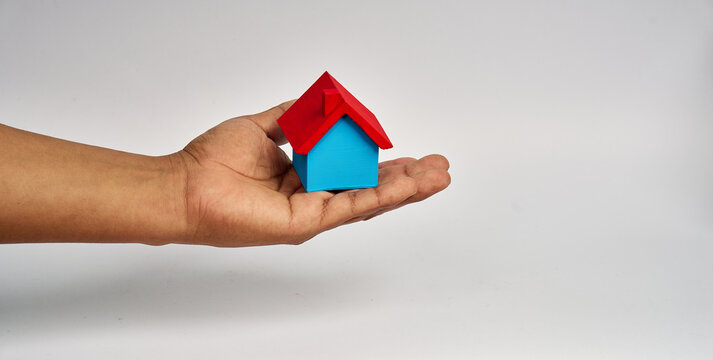 Hand holding miniature blue house with red roof