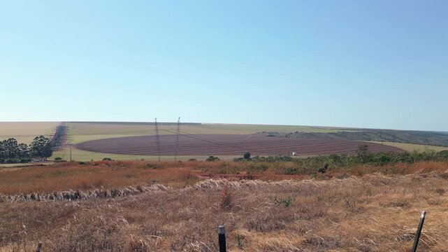 Mechanized arable fields show dark freshly tilled soil and parallel furrows near Sao Joao d'Alianca, Goias, Brazil, across rolling Cerrado farmland, drone forward flyover.
