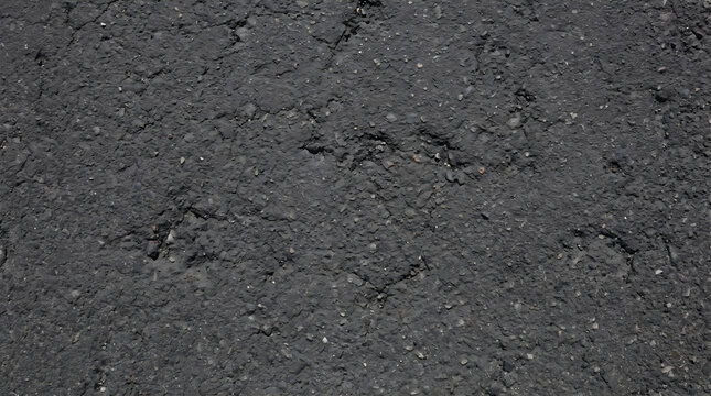 Worn dark grey asphalt road surface with embedded aggregate