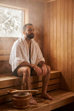 Man relaxing with eyes closed in a steamy wooden sauna