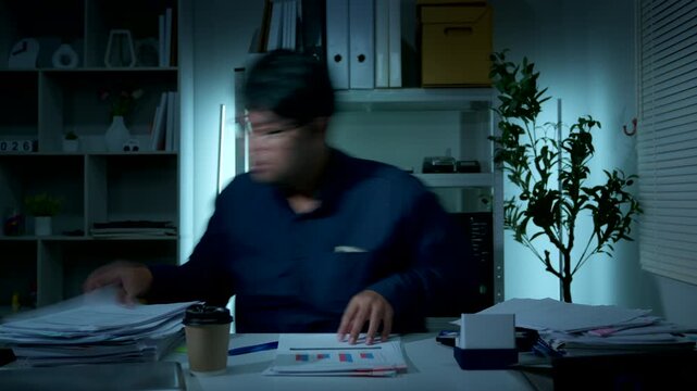 Frustrated businessman reviewing financial paperwork with head in hands at office desk
