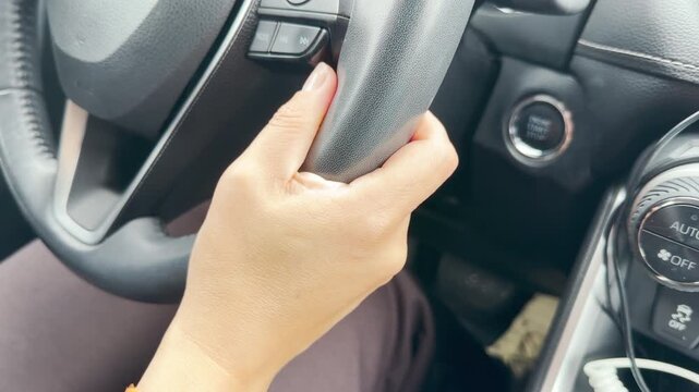 A person's hand firmly grips the steering wheel inside a modern car. The driver feels calm and confident on the road. This safe journey brings a feeling of peace.