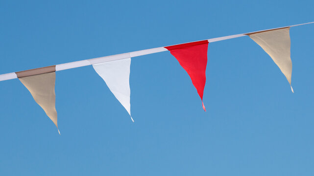 Bright red and white triangular flags hang against clear blue sky