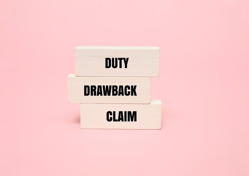 Wooden blocks with text "DUTY DRAWBACK CLAIM" on pink background. Concept for customs refund, tax policy, and trade logistics