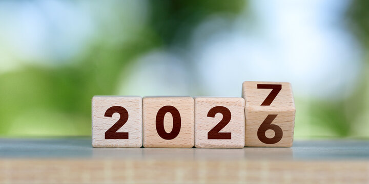 2027 Happy new year concept. Wooden cube block change from 2026 to 2027 on green bokeh background for fresh beginnings, annual change, future planning, countdown. Business resolutions goals