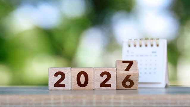 2027 Happy new year concept. Wooden cube block change from 2026 to 2027 on green bokeh background for fresh beginnings, annual change, future planning, countdown. Business resolutions goals