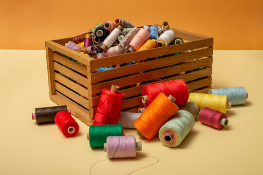 A box with multi colored coins of different threads on a colored background