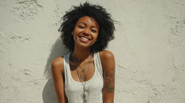 Smiling african female adult with curly hair against white wall