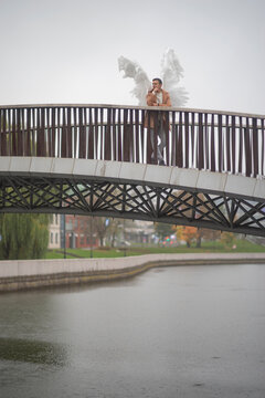 Angel man standing on pedestrian city bridge over river with copy space