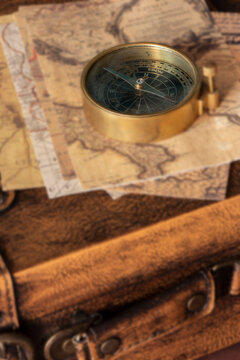 Old vintage maps and brass compass on top of a vintage leather luggage case. Vintage travel background backdrop concept.