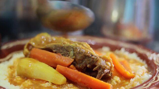 Close-up of broth poured over beef and carrots on Moroccan couscous