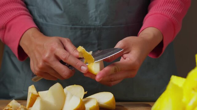 Peeling a Fresh Asian Pear with a Kitchen Knife on a Wooden Cutting Board