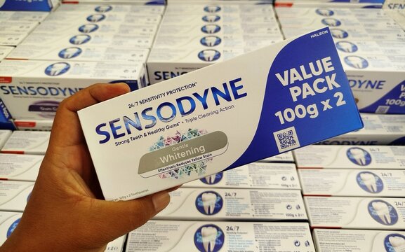 KUALA TERENGGANU, MALAYSIA- OKTOBER 13. 2026: Hand holding Sensodyne Gentle Whitening toothpaste value pack box, ideal for oral care and personal hygiene stock photo metadata tags.