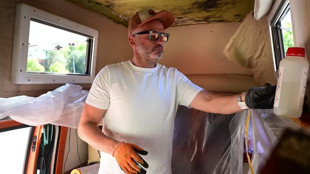 Man cleaning mold and restoring the interior of a camper van