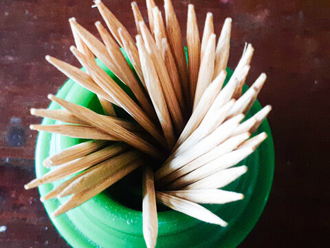 Wooden Toothpicks in a Green Plastic Holder on a Wooden Table