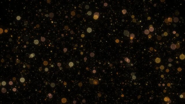 Glowing particles dispersing across a dark background. Scattered luminous specks spread through the frame, forming an abstract dust effect with fading points and changing concentrations of light.