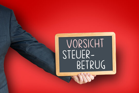 orsicht Steuerbetrug &ndash; Person im Anzug h&auml;lt Tafel als Warnung vor Steuerhinterziehung und Wirtschaftskriminalit&auml;t