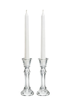 Two elegant white taper candles stand upright in clear glass candlesticks on a clean white background