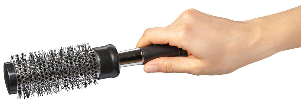 Hand holding a round hair brush for styling hair in a bathroom setting