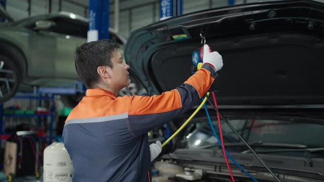 Car lies system of manometers for refueling air conditioner. Car refilling air condition in air shop. The hands of the master unscrew the protective cap of the air conditioner