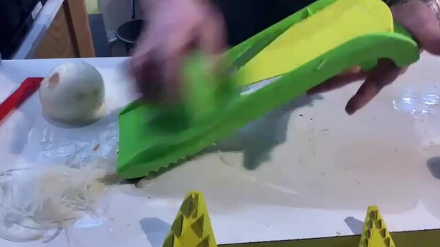 hands cutting potato into slices for a gratin in the kitchen