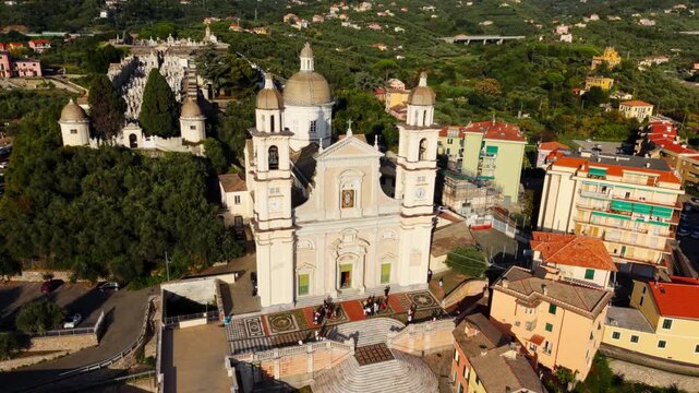 Wedding guests linger on the steps of a hilltop Italian church as a drone glides overhead revealing the colorful town around it.