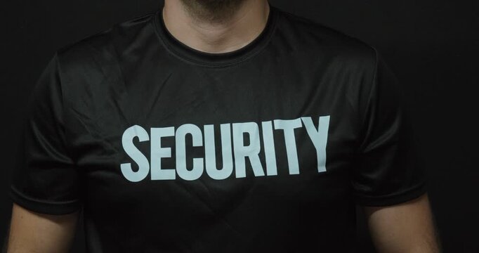 Close-up of a man wearing a black security T-shirt. Concept for professional security service, protection, safety, guarding and access control.