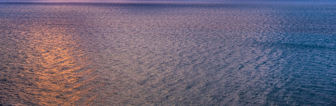 Calm ocean surface reflecting sunlight at sunrise