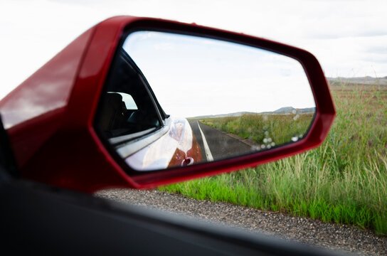 Close-up of side view mirror of car on rural road
