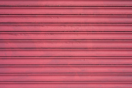 Dusty pink metal roller shutter texture with horizontal slats and weathered paint