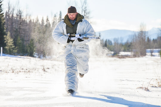 A hunter wearing  a coldweather camouflage outfit carries his rifel