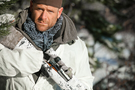 Man in white winter camouflage with a rifle