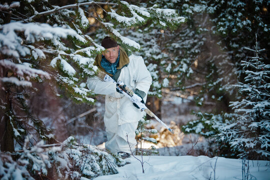 A man wearing  a coldweather camouflage outfit carefully moves