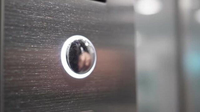 Finger presses elevator button and ring illuminates. Elevator operation. Modern building access. Close-up of lift control. Clean modern design and soft light. A smooth and quiet ride.