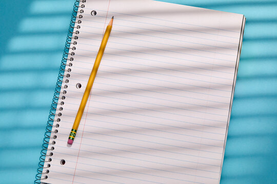 Spiral notebook and pencil on blue background
